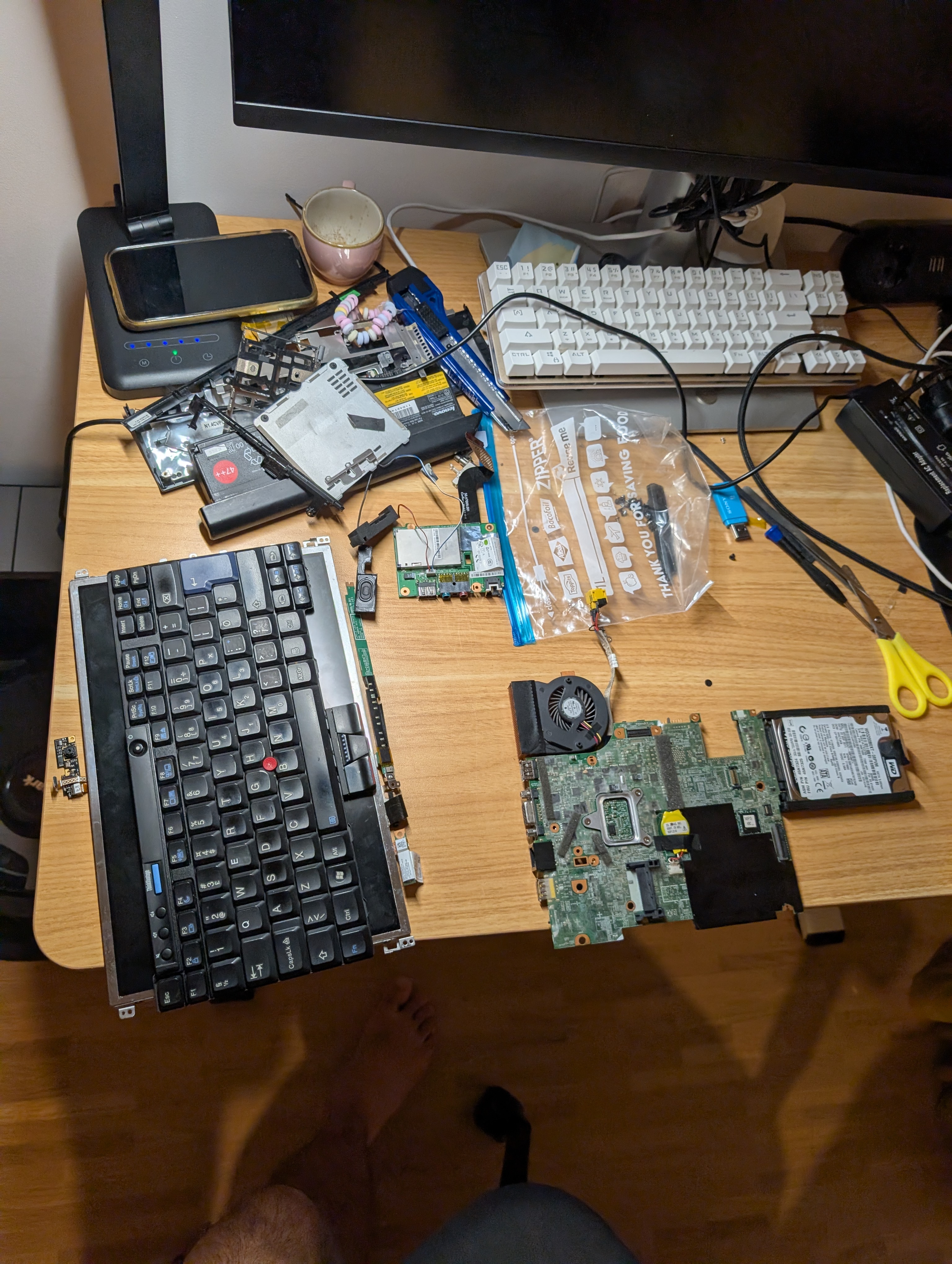 Lenovo ThinkPad X201 fully disassembled on a desk, with motherboard, keyboard, screen and other parts laid out